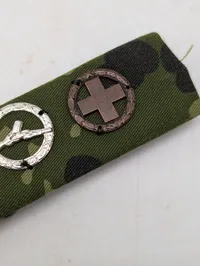 Militær bånd med fire færdighedstegn på camouflagebund