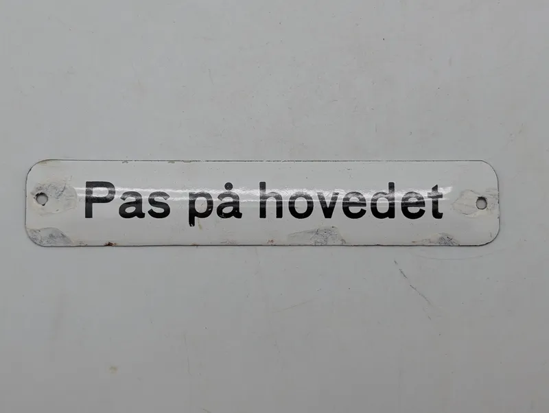 Emaljeskilt med teksten "Pas på hovedet" DSB