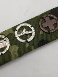 Militær bånd med fire færdighedstegn på camouflagebund